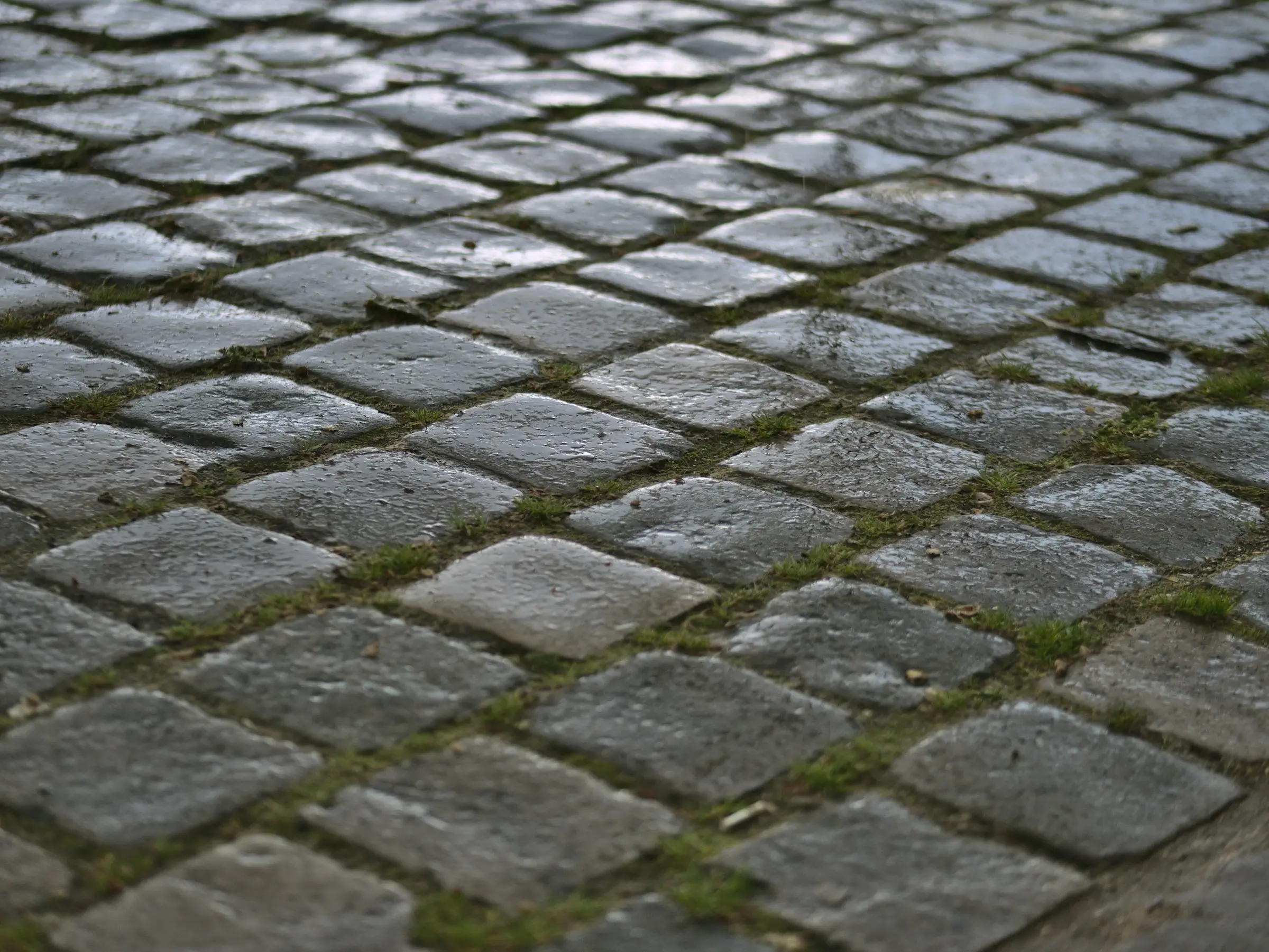 Driveway laid in grey block paving in a herringbone pattern in front of a garage